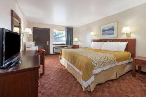 a hotel room with a bed and a flat screen tv at Days Inn by Wyndham Russell in Russell