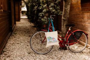 czerwony rower zaparkowany obok drzewa z torbą w obiekcie Camping La Pineta w mieście Porto Recanati