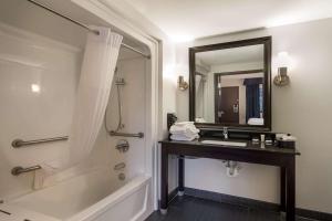 a bathroom with a tub and a sink and a mirror at Clarion Pointe Downtown in Syracuse