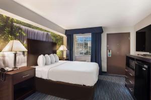 a hotel room with a bed and a television at Clarion Pointe Downtown in Syracuse