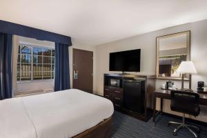 a hotel room with a bed and a desk and a television at Clarion Pointe Downtown in Syracuse