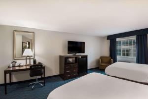 una camera d'albergo con letto, scrivania e TV di Clarion Pointe Downtown a Syracuse Altre 20 foto