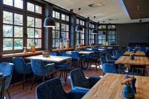 a restaurant with wooden tables and blue chairs at ATLANTIC Hotel Landgut Horn in Bremen