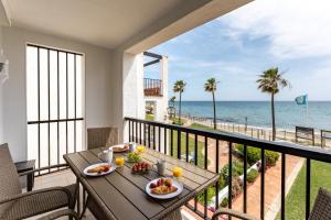 balcón con mesa y vistas al océano en Sea Front Beach house Micaela G, en Marbella