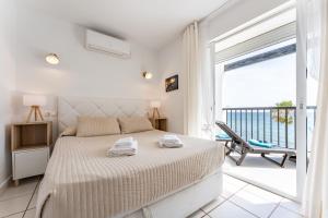 a white bedroom with a bed and a balcony at Sea Front Beach house Micaela G in Marbella +18 photos