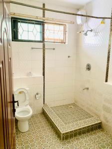 a bathroom with a shower with a toilet at Lux Suites Furaha Holiday Apartments Nyali in Mombasa