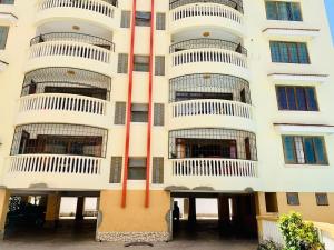 a tall white building with many windows at Lux Suites Furaha Holiday Apartments Nyali in Mombasa