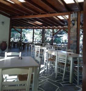 a dining room with white tables and white chairs at Παλιό κελάρι σε πέτρινο σπίτι in Áno Potamiá