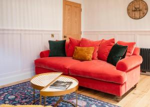 a red couch with colorful pillows in a living room at The Seelies - Luxury Aparthotel - By The House of Danu in Kingussie