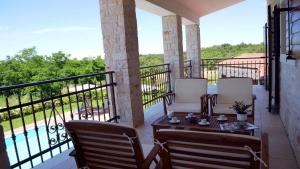 a balcony with a table and chairs and a pool at Spacious poolside villa with beautiful garden in Kringa in Pinezići