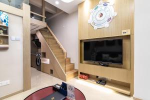 a living room with a large television and a staircase at Cloud Land Apartment 翡翠华庭 in Guangzhou