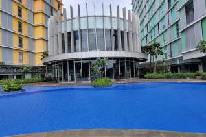 uma grande piscina azul em frente a um edifício em Apt Pejaten Park 1BR Latte w/ Netflix em Jakarta