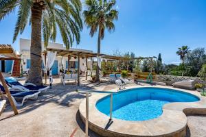 a swimming pool with palm trees and a house at Cas Padri by dracmallorca in Santanyi
