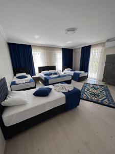 three beds in a room with blue curtains at Paradise House Hotel in Pamukkale