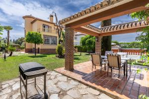 patio ze stołem i krzesłami pod pergolą w obiekcie Cypress House w mieście La Zubia