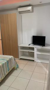um quarto com uma cama e uma secretária com uma televisão em Flat Village - Aldeia das Águas em Barra do Piraí