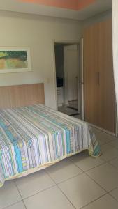 een slaapkamer met een bed met een gestreepte deken erop bij Flat Village - Aldeia das Águas in Barra do Piraí