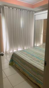 a bedroom with a bed and a window with curtains at Flat Village - Aldeia das Águas in Barra do Piraí