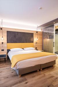 a bedroom with a large bed with a yellow headboard at Hotel Piccola Baita in Molveno