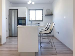 a kitchen with white counter tops and stools at Phaedrus Living: City Flat Rafaella 6 in Nicosia