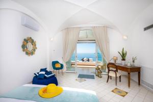 een slaapkamer met een bed en een bureau met uitzicht op de oceaan bij YourHome - Villa Aldo Marino in Positano