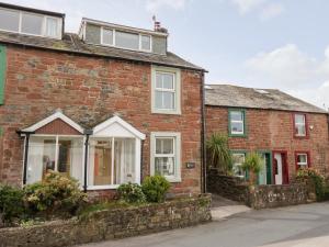 an old red brick house with white windows at Wainwright Cottage in Seascale