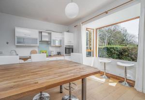 uma cozinha com uma mesa de madeira e uma grande janela em The Moorings- near the sea em Tramore