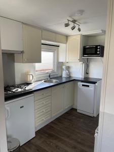 a kitchen with white cabinets and a sink at Chalet Zeeweg in Nunspeet +11 photos