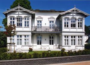 ein weißes Haus mit Balkon darüber in der Unterkunft Schöne Ferienwohnung in Seebad Bansin 200m vom Strand (Heringsdorf, Kaiserbäder, Usedom) in Bansin