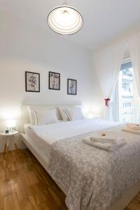 a white bedroom with a large white bed and a window at Vedrana-Free garage in Zagreb