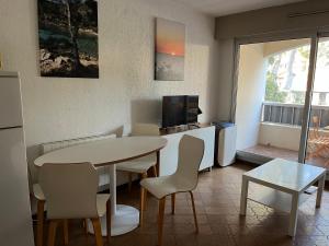 un salon avec une table, des chaises et une télévision dans l'établissement STUDIO SAINT MANDRIER, à Saint-Mandrier-sur-Mer