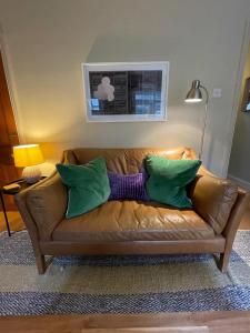 a brown leather couch with green and purple pillows at Beautiful & Cosy 2BD House - Southwark in London