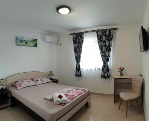 a bedroom with a bed and a desk and a window at Vila Bya in 2 Mai