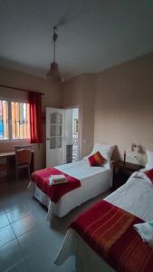 - une chambre avec 2 lits, une table et une fenêtre dans l'établissement Casa Las Vidrieras, à Puerto Real