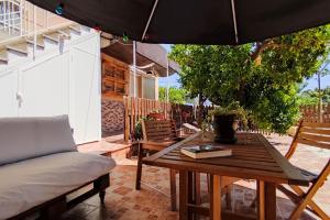 a patio with a table and a chair and an umbrella at Casa de invitados tradicional con piscina en la huerta de Lorca in Lorca