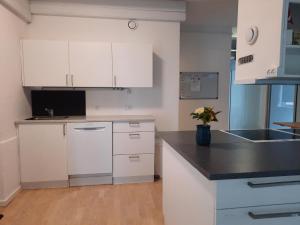 cocina con armarios blancos y encimera negra en Private Room in a shared apartment, en Odense