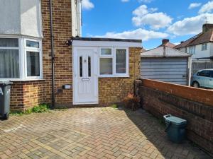a brick house with a white door and a brick wall at Amazing 1 bed flat near Heathrow in Feltham
