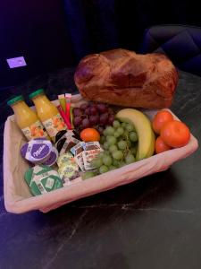 un vassoio di prodotti alimentari con frutta all'uva e una pagnotta di pane di Love room avec jacuzzi privé a Bonnétable