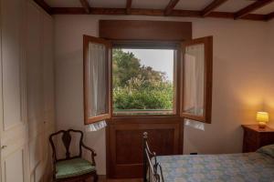 a bedroom with a window with a chair and a bed at [Sea Garden] Elegant Villa with a View in Rio nellʼElba