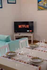 un tavolo con piatti e bicchieri da vino e una TV di [Sea Garden] Elegant Villa with a View a Rio nellʼElba