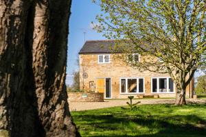 uma casa de tijolos com árvores em frente em Fletland Mill and Holiday Hamlet - 18th century watermill, in stunning location near Stamford em Stamford