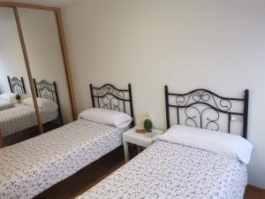 two beds in a room with two mirrors at Apartamento Llanes Mar y Monte in Llanes