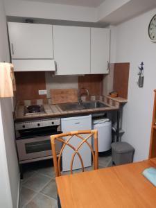 cocina con armarios blancos, fregadero y mesa en Residence Sole Dell'Argentario, en Porto Santo Stefano