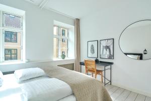 a white bedroom with a bed and a desk and windows at Spacious Flat Centrally Located in CPH's Old Town in Copenhagen