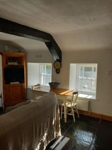 a bedroom with a bed and a table and two windows at Eddie's Roadside Thatched Cottage 