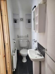 biała łazienka z toaletą i umywalką w obiekcie Eddie's Roadside Thatched Cottage 