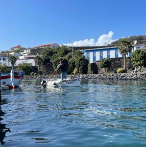 a man is rowing a boat in the water at Casa do Porto in Angra do Heroísmo