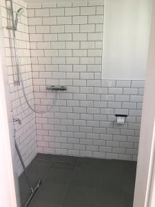 a white tiled shower with a hose in a bathroom at Apartmaji Sara, Izola - Isola in Izola