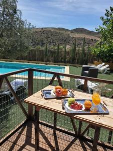 a table with fruit and juice on it next to a pool at Casa Los Bartolos in Vélez-Rubio