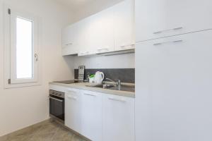 Una cocina con gabinetes blancos y un fregadero. en Casa Fischio, en Castelsardo 5 fotos más